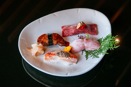 白盘上的寿司鹅草大雄海鲑鱼深底背景温暖的语调图象大米高清图片素材