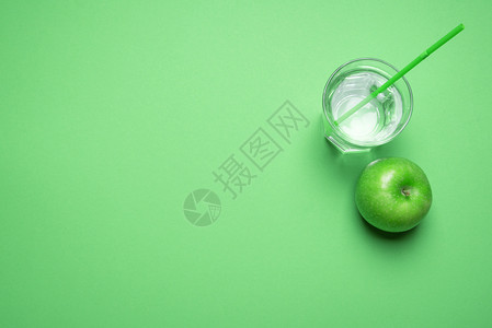上方是一片绿苹果靠近一杯有稻草的水绿色背景最低要求戒毒概念健康饮食素图片