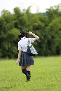 绿色雨伞在有草山和树的农村学校背景