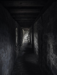在中世纪的建筑物里在低光下有天候的通道光束一个长的走廊有阴影最后光线老旧的建筑图片