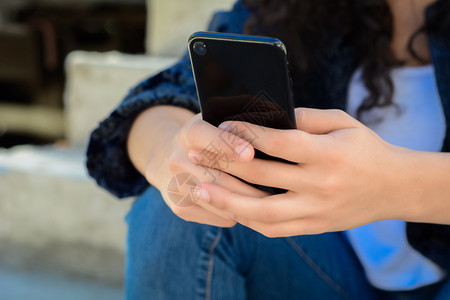 美丽的年轻女子在街上用智能手机发信息图片