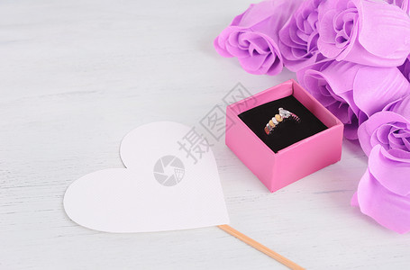 粉红盒中的金钻环上面有粉红玫瑰和情人节r以白木背景塑造的心型卡片情人节和日概念图片