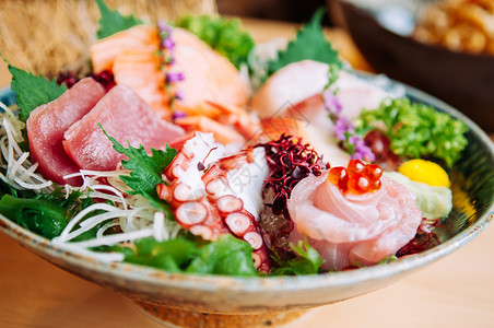 章鱼寿司在手工艺陶瓷碗中紧地拍下手工艺陶瓷碗中的日本新鲜洋葱金鱼沙西米阿托罗塔科鲑鱼大马奇和沙比背景