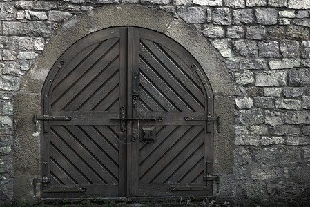 封闭的木制门中世纪结构有坚固的金属链和古建筑的石墙图片