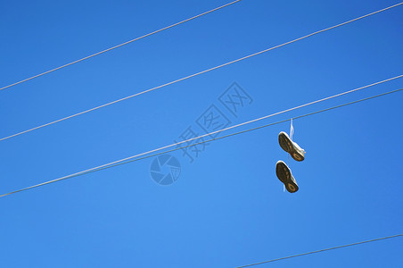 穿旧鞋挂在一条针对蓝天的电线上图片