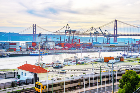 Lisbon商业港口25April桥和JesuChrit纪念碑装有起重机的码头集装箱城市列车和停靠在岸边利斯本脚下的船只Lisb图片