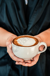 女手举着一杯咖啡热卡布奇诺上面有漂亮的牛奶近镜头图片