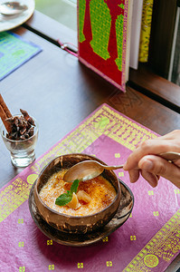 法国甜点勺子挖在美丽的奶油香草花椰子贝壳上彩色板垫图片
