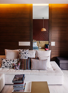 2014年6月日2014年bangko泰国现代客厅有多彩的亚洲沙发一堆书籍织物枕头天花板灯和木墙现代家庭室内装饰图片