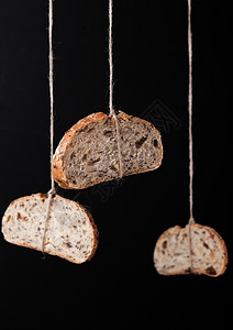 鲜烤面包燕麦挂在绳上黑色背景图片