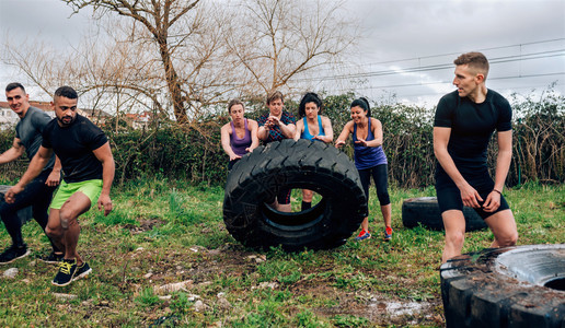 一组女参与者在障碍课程中转动卡车车轮障碍课程的女参与者转动轮子图片