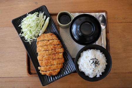 Tonkatsu炒猪肉切菜加大米和木桌上的日本菜汤图片