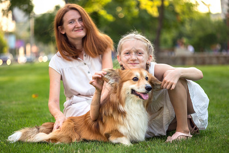 母亲和女儿Corgifluy坐在草坪上看着镜头图片