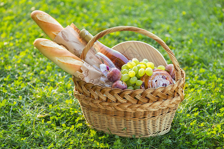 夏季在草地上野餐面包葡萄眼镜和卷子放在绿草上背景图片