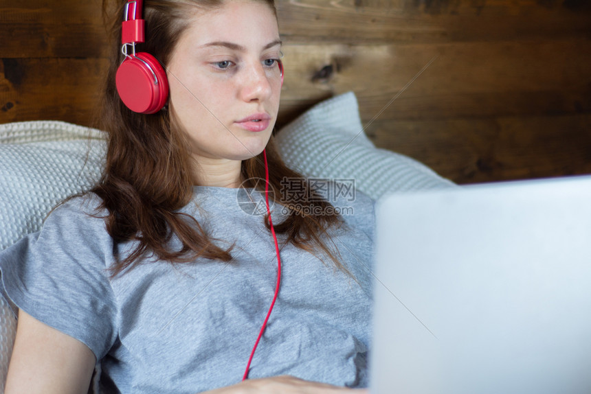 年轻女孩在床上听音乐看电影
