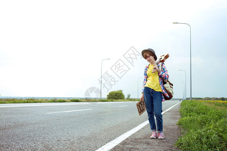 年轻女孩带着吉他沿路走来搭便车图片