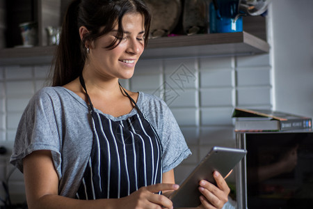 年轻妇女在家中厨房用数字平板电脑烹饪和食谱健康品图片