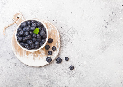 鲜生有机蓝莓在厨房背景上以白瓷碗为叶子图片