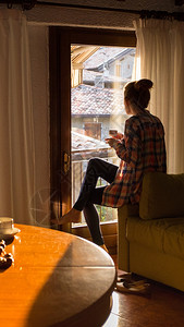 女孩坐在沙发上喝着咖啡看窗外图片
