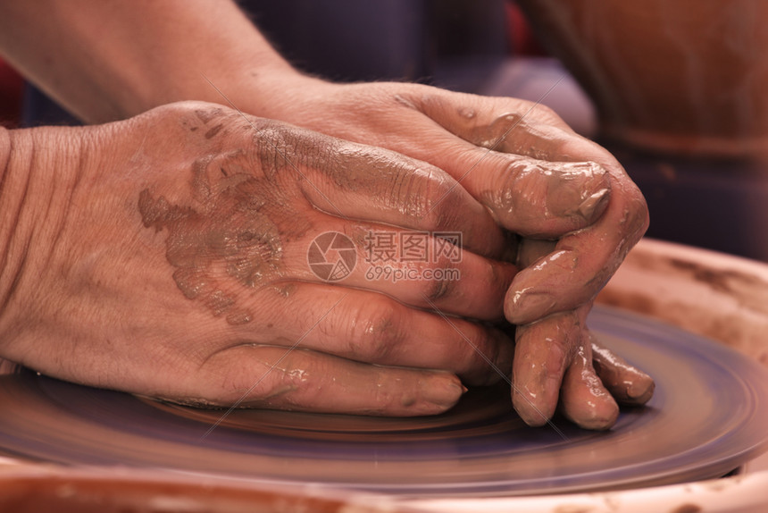 人手在陶匠的车轮上用粘土塑造图片