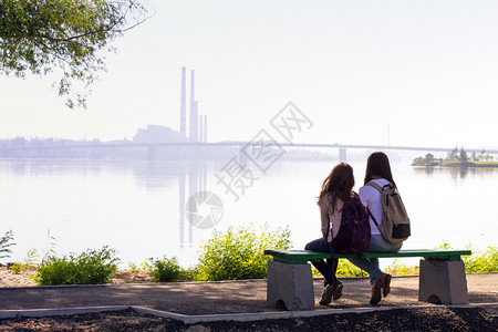 两个十几岁的女孩背坐在德尼伯河的岸上图片