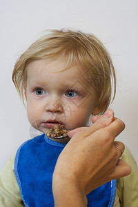 小女孩抱着勺子在她的怀里吃着一顿便饭图片