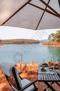 湖边野餐下午茶桌布满许多食物和饮料背景图片