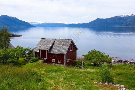 在峡湾海岸的红挪威农村住宅图片
