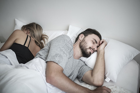 夫妻在床上睡觉彼此忽视对方避免行为有冲突或问题的概念图片