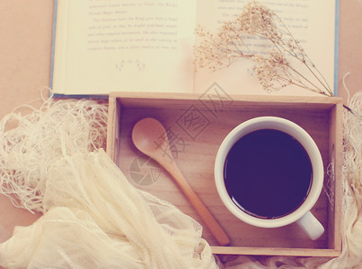 黑咖啡和勺子放在木托盘上带有书本反转过滤效果图片