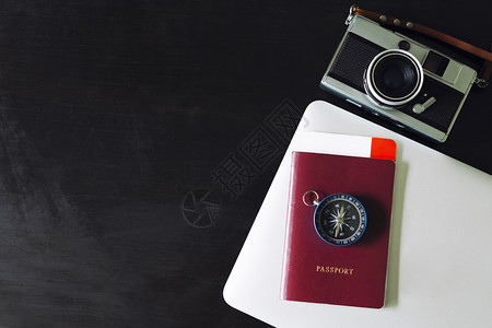 护照和笔记本电脑放在黑桌上图片