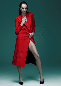 时装模型湿头发穿绿色背景的红长大衣背景图片