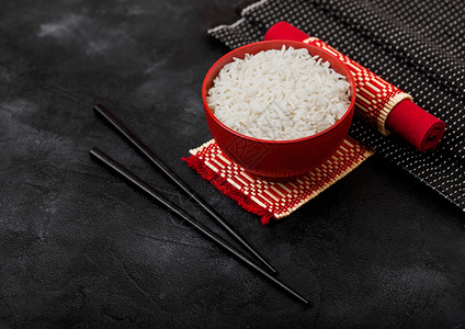 红碗加煮的有机巴斯马提茉米饭竹制地皮上有黑筷子石底有红皮巾图片