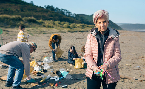 爷爷和孙女志愿者在海滩上拾取塑料吸管背景图片