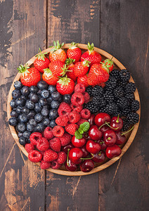 黑木桌底的圆盘中新鲜有机夏季果子混合物草莓蓝黑和樱桃图片