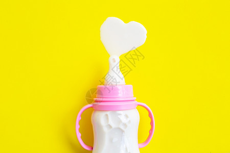 产品手册黄色背景的婴儿奶瓶心形状顶视图背景