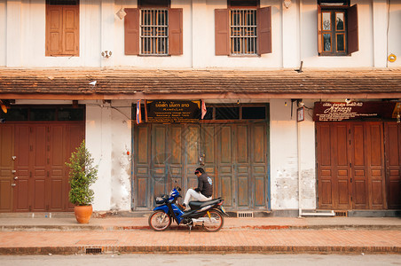 2019年4月4日老挝琅勃拉邦木门法国殖民建筑和当地人在主街骑摩托车老挝著名的交通工具图片