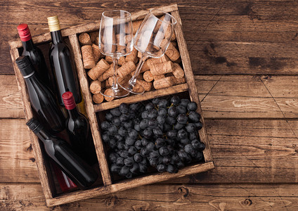 红酒小瓶子和杯空黑葡萄有软木塞和开瓶器装在旧木箱里放制本底图片