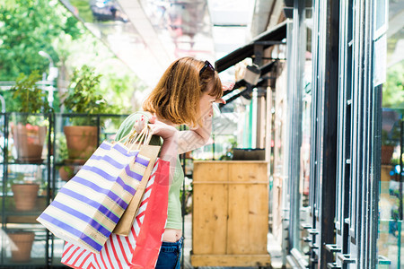 有购物袋的年轻红发女青看市内商店购物和生活方式概念图片