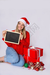 穿着圣诞帽和在工作室拿着黑板的年轻美女肖像圣诞节概念图片