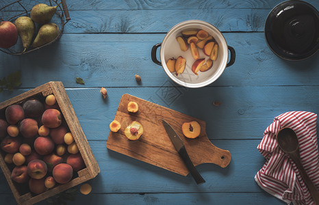 木箱里有新鲜桃子和杏仁在切削板上水果在蓝桌上做桃果酱面看家用烹饪果酱背景图片