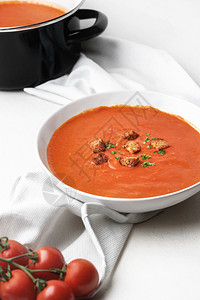 西红柿汤碗自制在白色厨房毛巾和桌子上碗里奶油汤的垂直图象健康的素食图片