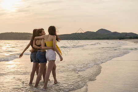 一群青年女人在日落的海边沙滩上开心玩水图片