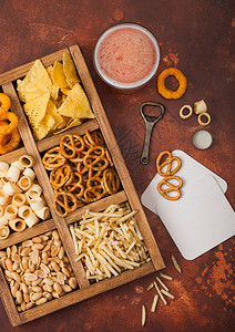 棕色厨房背景的一盒零食脆饼盐土棍花生洋葱圈图片