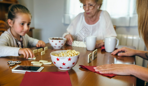 祖母女儿和孙在客厅玩多米诺游戏图片