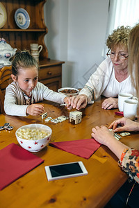 祖母女儿和孙在客厅玩多米诺游戏三代女在玩多米诺游戏图片