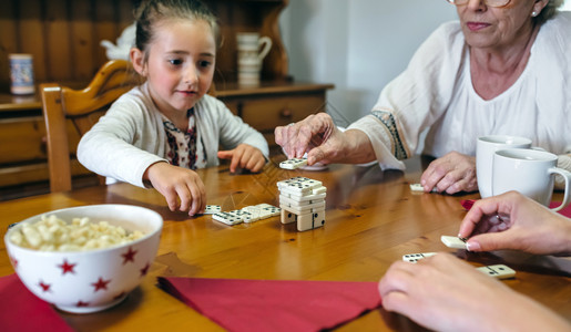 祖母女儿和孙在客厅玩多米诺游戏三代女在玩多米诺游戏图片