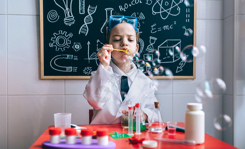 小男孩科学家在桌外玩肥皂泡对抗抽黑板小孩用肥皂泡对抗抽黑板图片