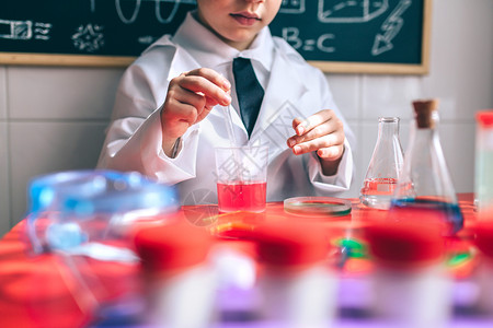 在红色桌子上玩着多彩液体小孩玩着用多彩液体做化学家图片