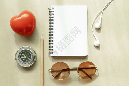 白笔记本空页上面有罗盘耳机太阳镜铅笔和红心图片